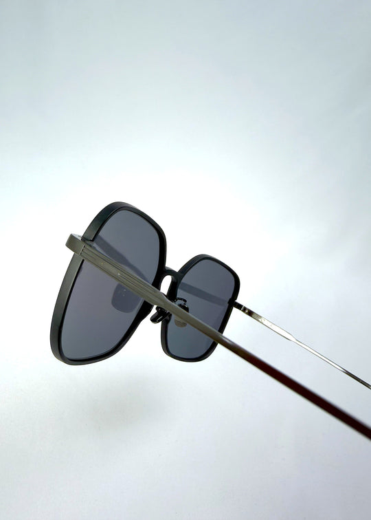 Close-up temple detail view of Spica sunglasses in Black, featuring an ultra-light frame with titanium temples and polarized lenses, showing the temple arm and hinge area. 