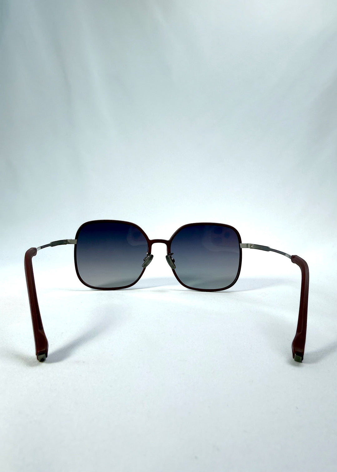 Back view of Spica sunglasses in Cherry Red, featuring an ultra-light frame with titanium temples and polarized lenses, showing the inside frame and open temples. 