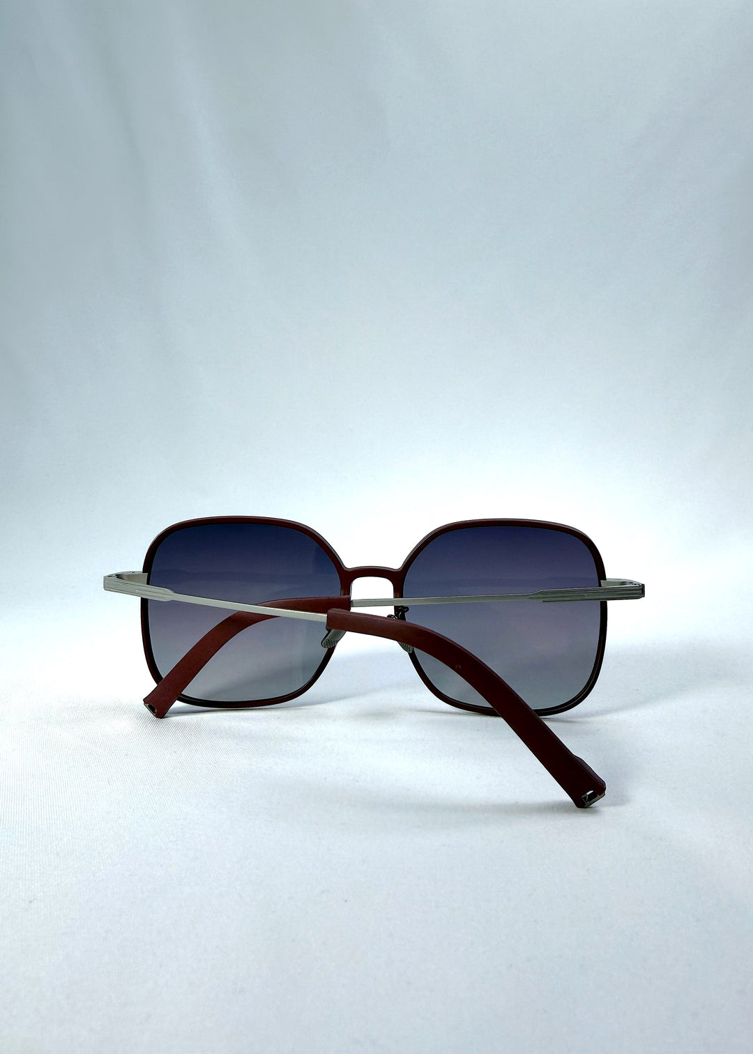 Folded view of Spica sunglasses in Cherry Red, featuring an ultra-light frame with titanium temples and polarized lenses, showing the folded temples and frame profile. 