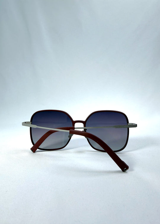 Folded view of Spica sunglasses in Cherry Red, featuring an ultra-light frame with titanium temples and polarized lenses, showing the folded temples and frame profile. 