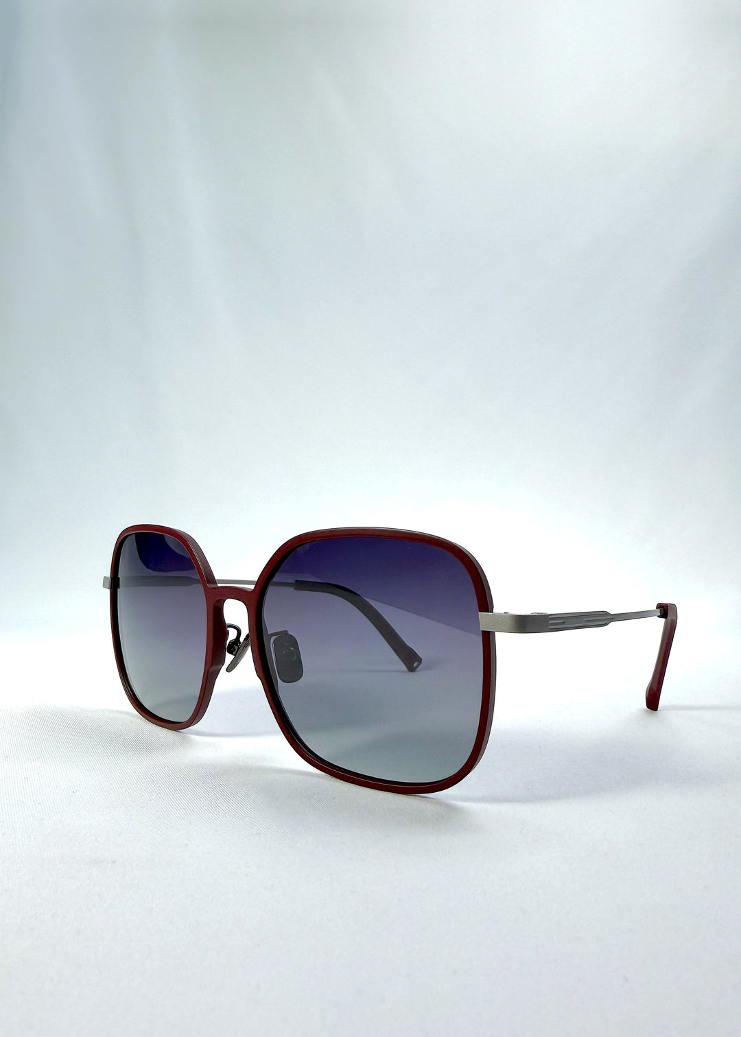 Three-quarter front view of Spica sunglasses in Cherry Red, featuring an ultra-light frame with titanium temples and polarized lenses, showing the front shape and temple profile. 