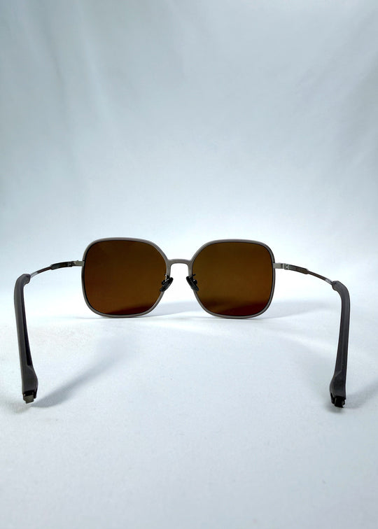 Back view of Spica sunglasses in Milk Tea Brown, featuring an ultra-light frame with titanium temples and polarized lenses, showing the inside frame and open temples. 