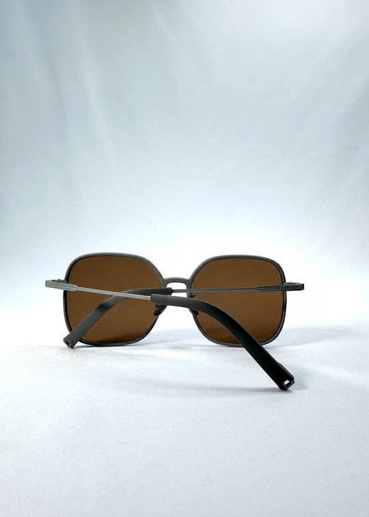 Folded view of Spica sunglasses in Milk Tea Brown, featuring light titanium frame and polarized lenses, showing the folded temples and frame profile.