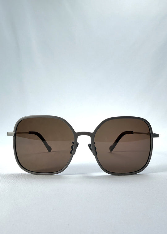 Front view of Spica sunglasses in Milk Tea Brown, featuring light titanium frame and polarized lenses, showing the full front silhouette.