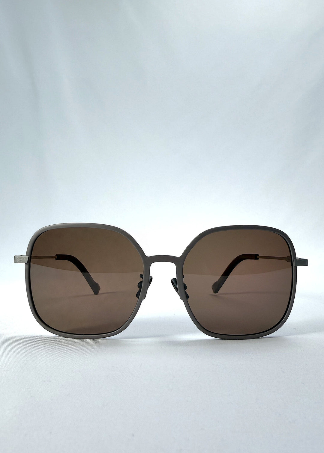 Front view of Spica sunglasses in Milk Tea Brown, featuring an ultra-light frame with titanium temples and polarized lenses, showing the full front silhouette. 