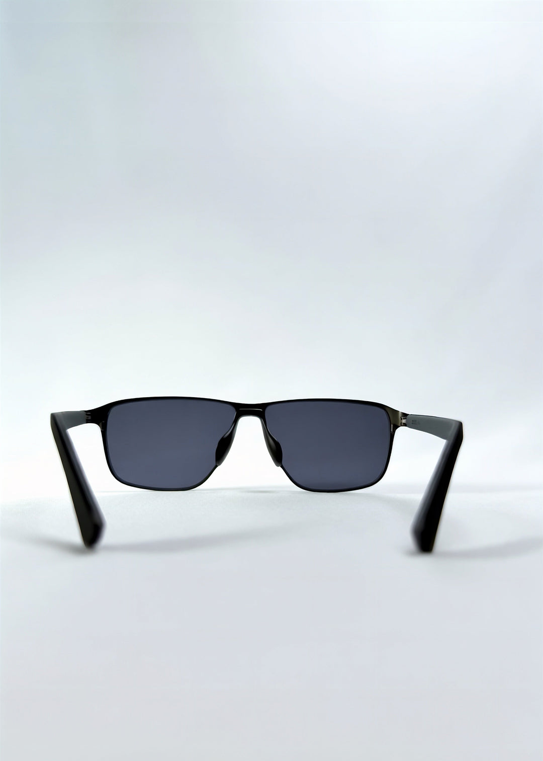 Back view of Vector Line sunglasses in Matte Black, featuring wide matte black rectangular metal frame and full grey polarized lenses, showing the inside frame and open temples. 