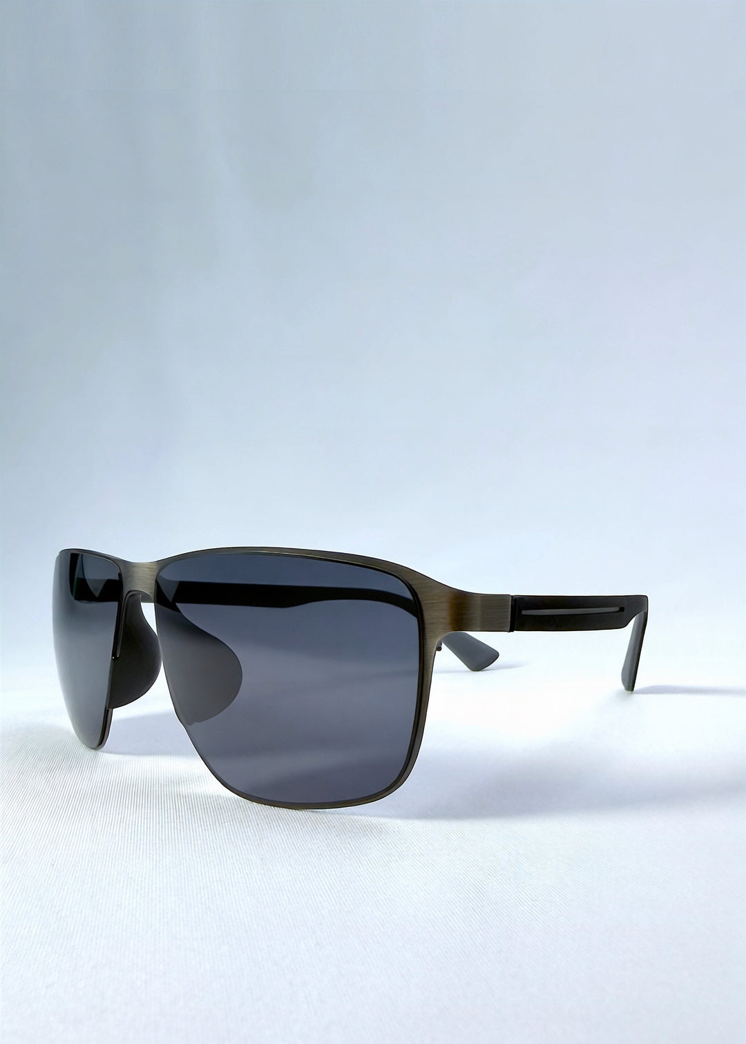 Three-quarter front view of Vector Line sunglasses in Matte Black, featuring wide matte black rectangular metal frame and full grey polarized lenses, showing the front shape and temple profile. 