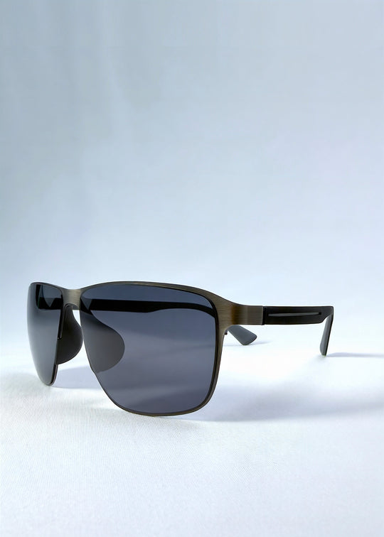 Three-quarter front view of Vector Line sunglasses in Matte Black, featuring wide matte black rectangular metal frame and full grey polarized lenses, showing the front shape and temple profile. 