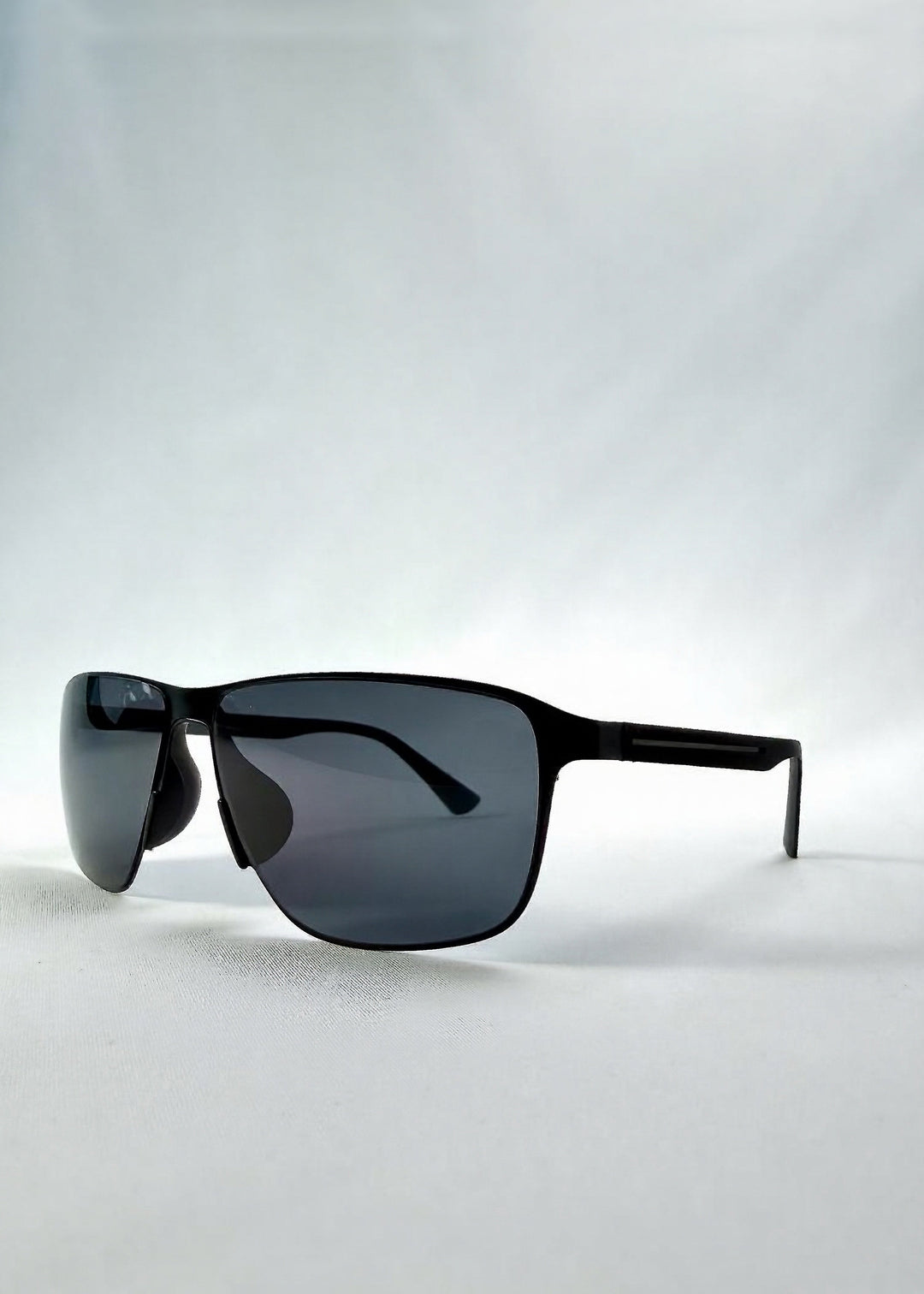 Three-quarter front view of Vector Line sunglasses in Violet Graphite, featuring wide gunmetal frame and violet-grey polarized lenses, showing the front shape and temple profile. 