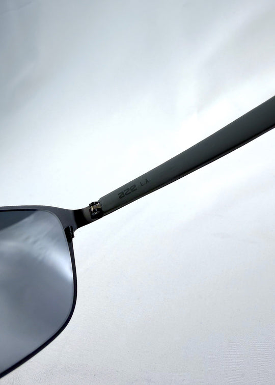 Close-up temple detail view of Vector Line sunglasses in Violet Graphite, featuring wide gunmetal frame and violet-grey polarized lenses, showing the temple finish and hinge connection. 