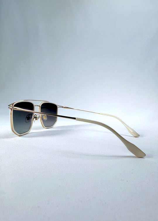 Back-angle view of AZE Vela Trace sunglasses in Glacial Smoke, featuring a pale gold-tone rectangular frame and blue-gray gradient lenses, showing the rear frame structure and temple alignment.