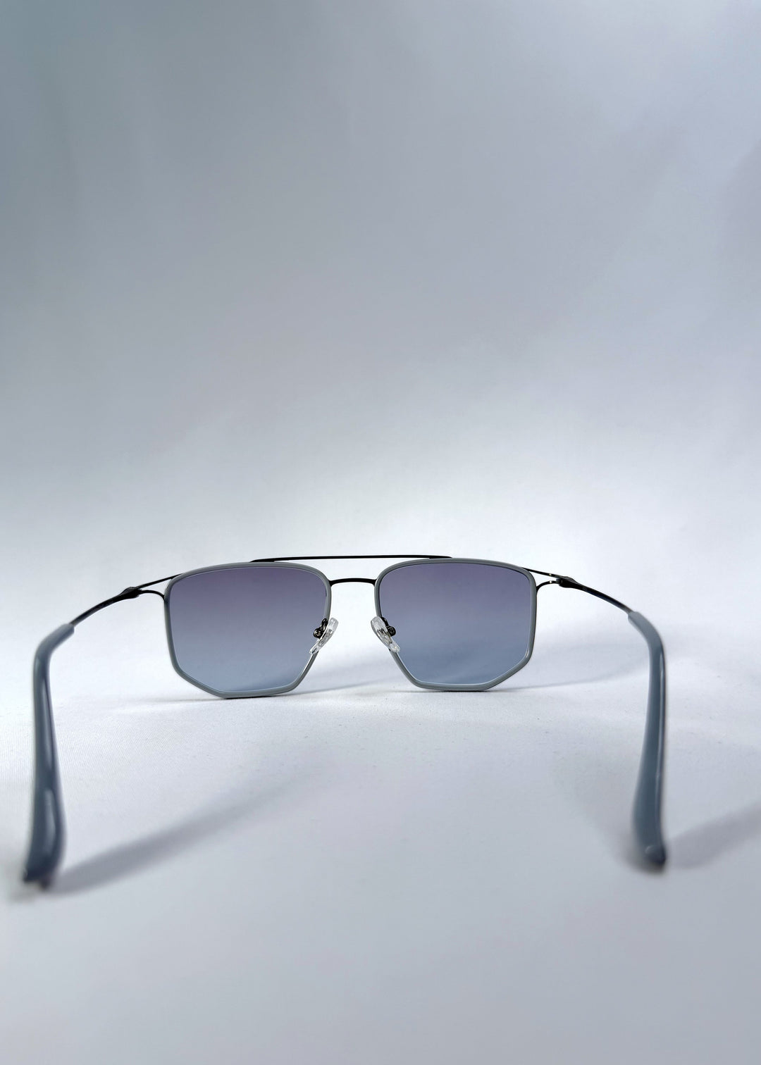 Back view of AZE Vela Trace sunglasses in Midnight Blue, featuring a gray-blue rectangular frame and blue-gray gradient lenses, showing the inner frame and open temples. 