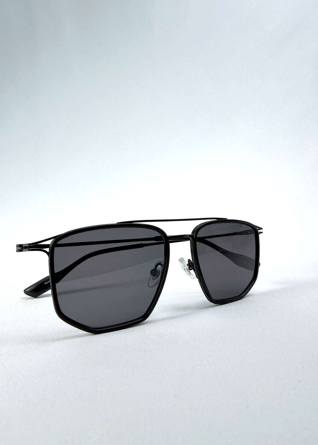 Folded view of AZE Vela Trace sunglasses in Obsidian Black, featuring a structured black rectangular frame and smoky gray lenses, showing the folded temples and frame profile.