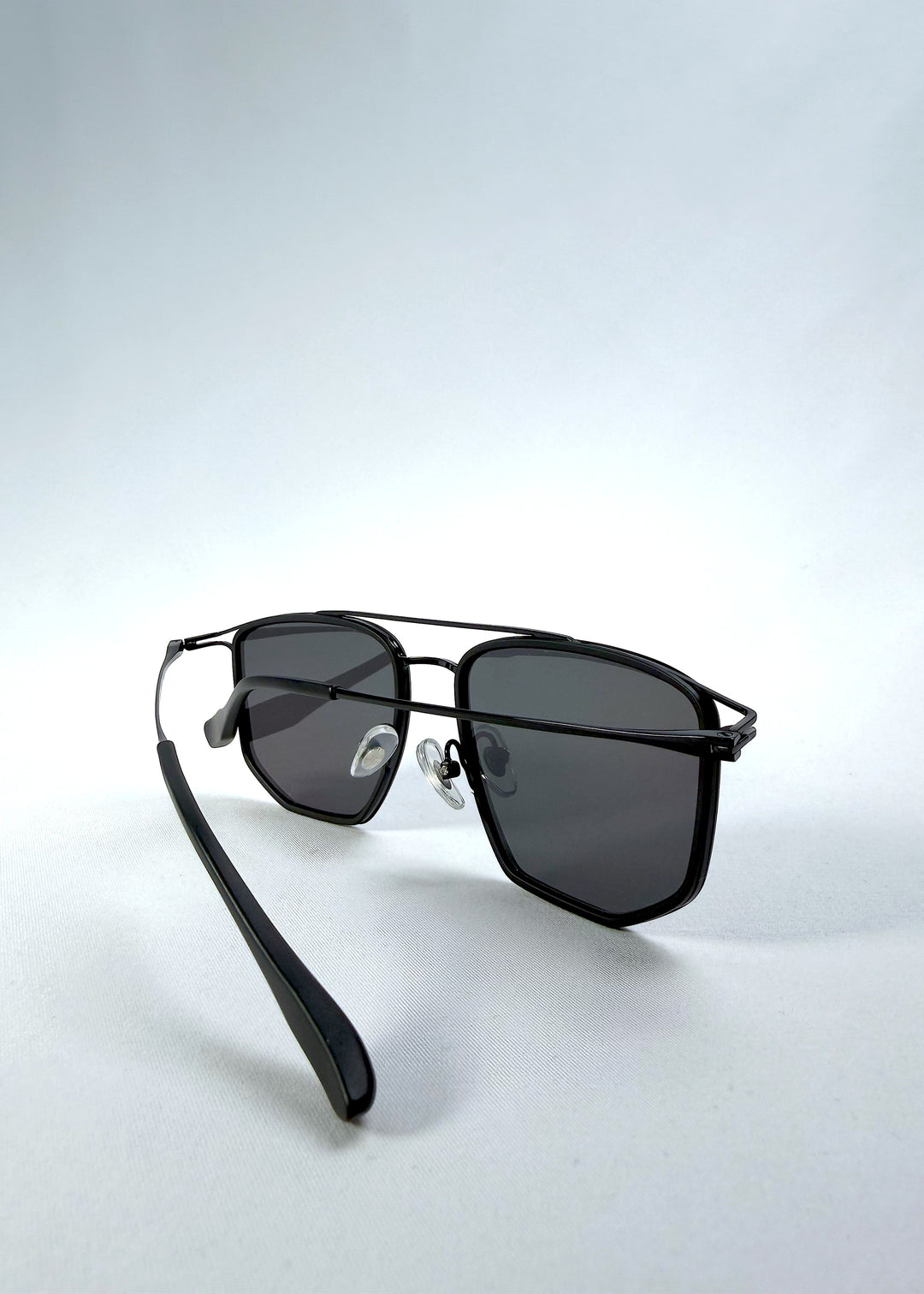 Inside-angle view of AZE Vela Trace sunglasses in Obsidian Black, featuring a structured black rectangular frame and smoky gray lenses, showing the inner frame, nose pads, and temple structure.