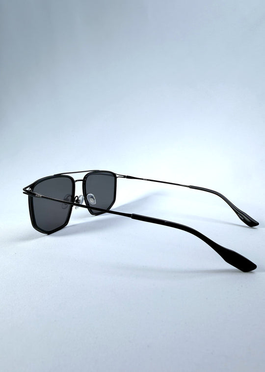 Side-angle view of AZE Vela Trace sunglasses in Obsidian Black, featuring a structured black rectangular frame and smoky gray lenses, showing the temple line and rear frame profile.