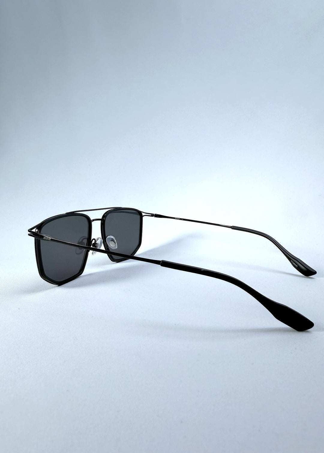 Side-angle view of AZE Vela Trace sunglasses in Obsidian Black, featuring a structured black rectangular frame and smoky gray lenses, showing the temple line and rear frame profile. 