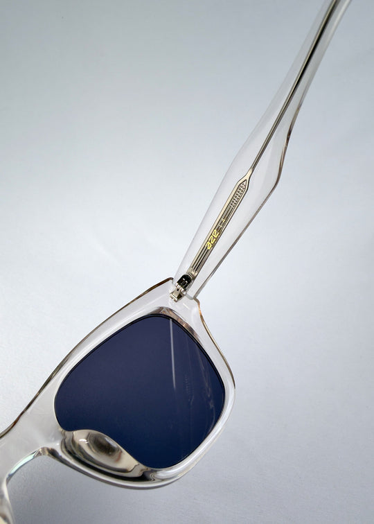 Close-up of the hinge and temple of Veyron in Crystal Static, showing the metal core embedded in the clear acetate. 