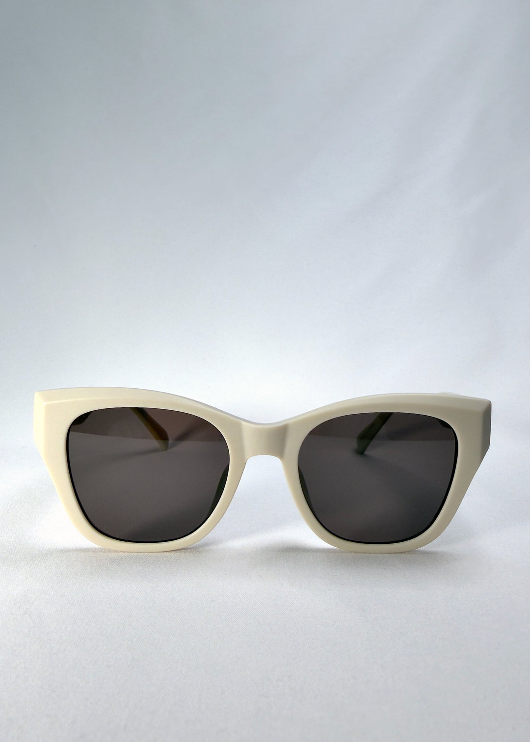 Front view of Veyron in Pale Mirage, showing the matte ivory acetate cat-eye frame and dark grey lenses. 