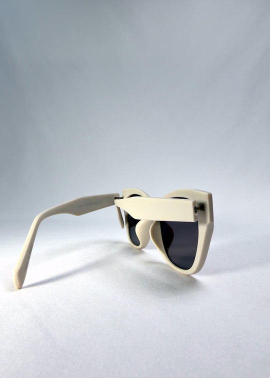 Left side-temple view of Veyron in Pale Mirage, showing the matte ivory acetate frame and dark grey lenses. 