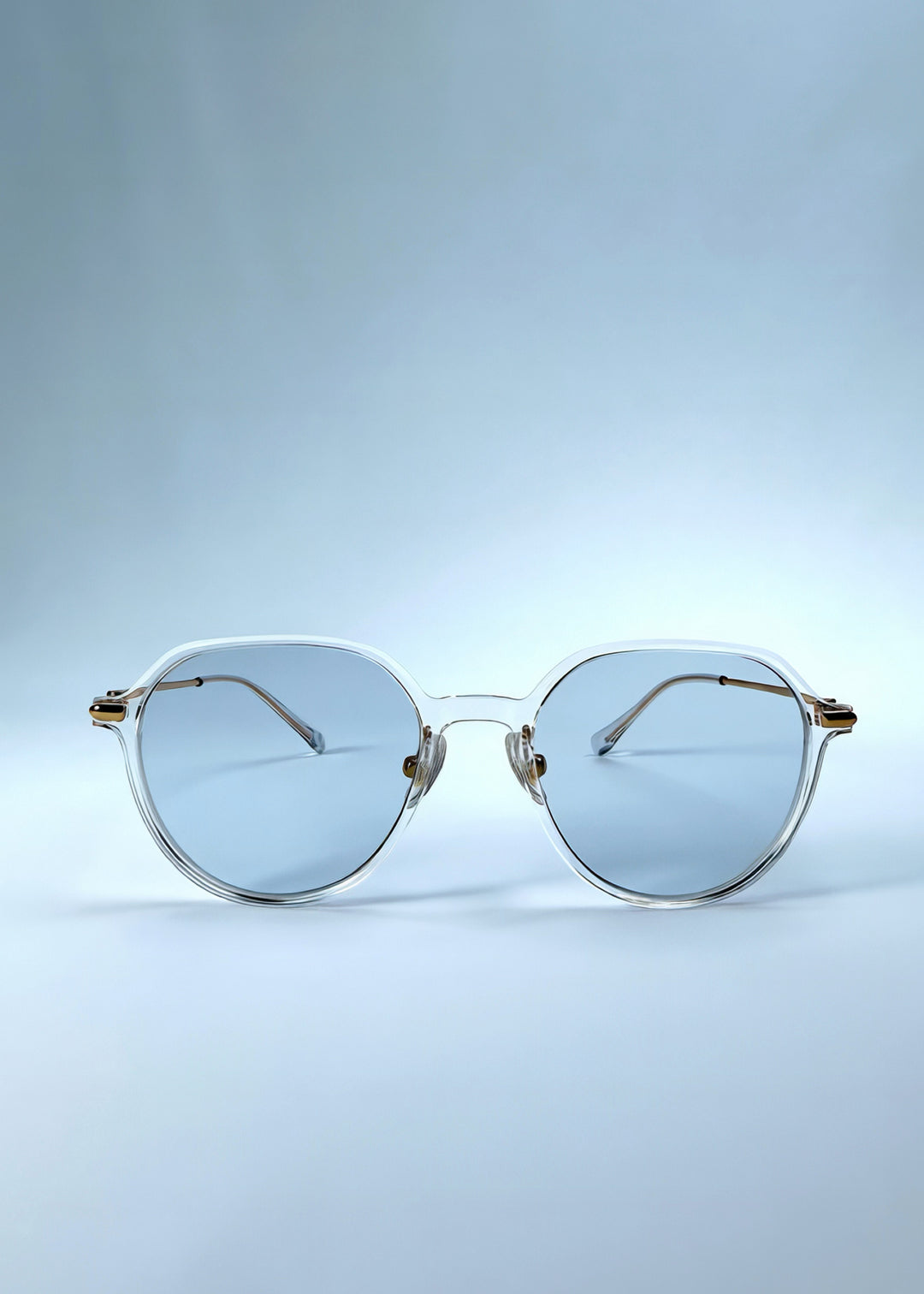 Front view of AZE Vireo Arc sunglasses in Crystal Static, featuring a crystal-clear frame, pale blue lenses, and gold-tone accents, showing the full front silhouette.