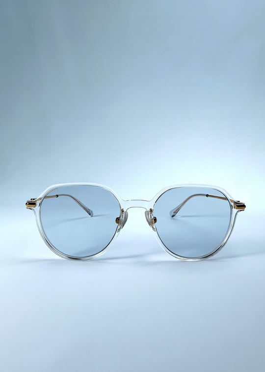 Front view of AZE Vireo Arc sunglasses in Crystal Static, featuring a crystal-clear frame, pale blue lenses, and gold-tone accents, showing the full front silhouette. 