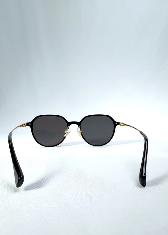 Back view of AZE Vireo Arc sunglasses in Duskgold, featuring a dark softly geometric frame, gold-tone accents, and smoky gray lenses, showing the inner frame and open temples.