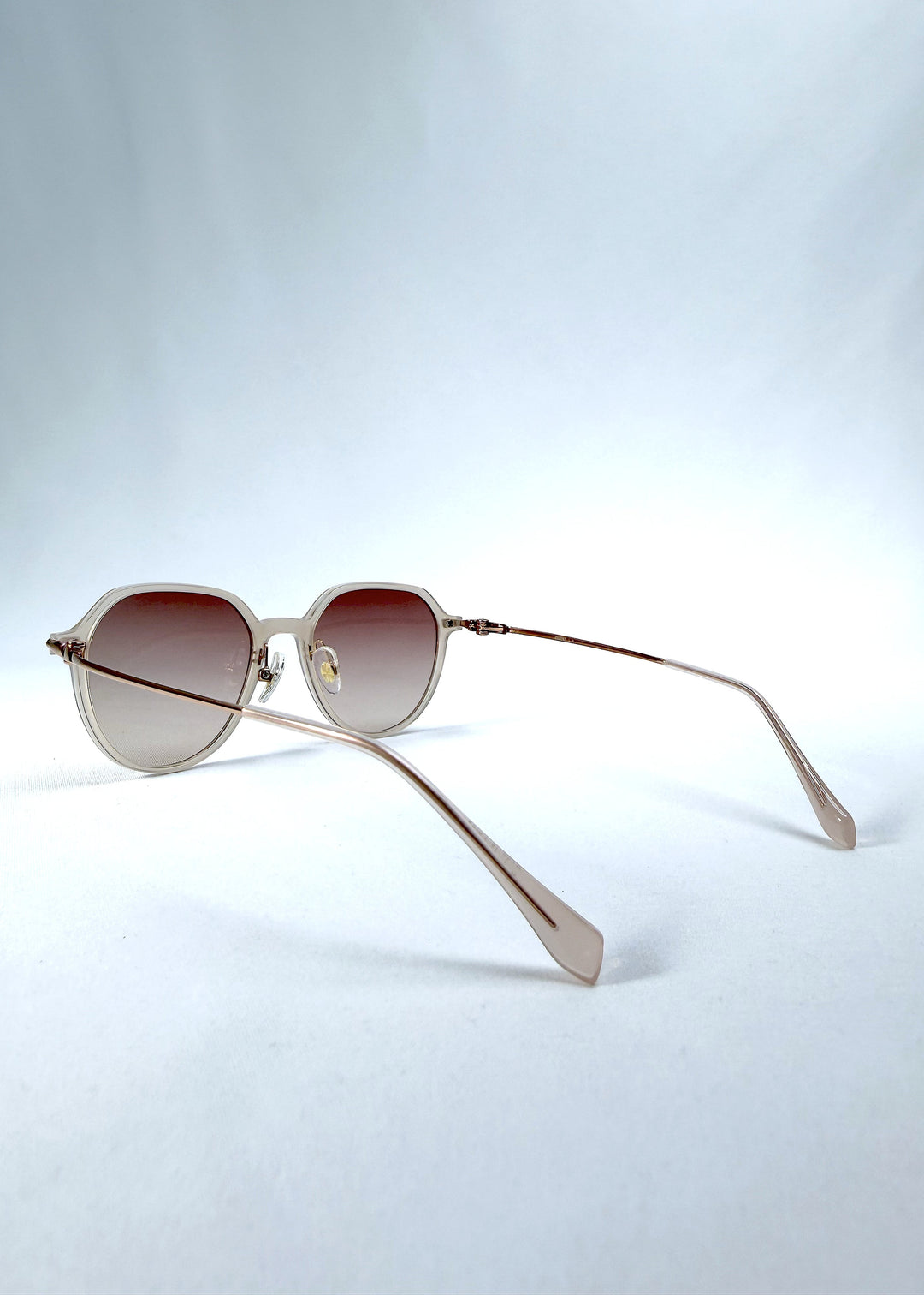 Back-angle view of AZE Vireo Arc sunglasses in Roselight, featuring a translucent ivory frame and soft rose gradient lenses, showing the rear frame structure and temple alignment. 