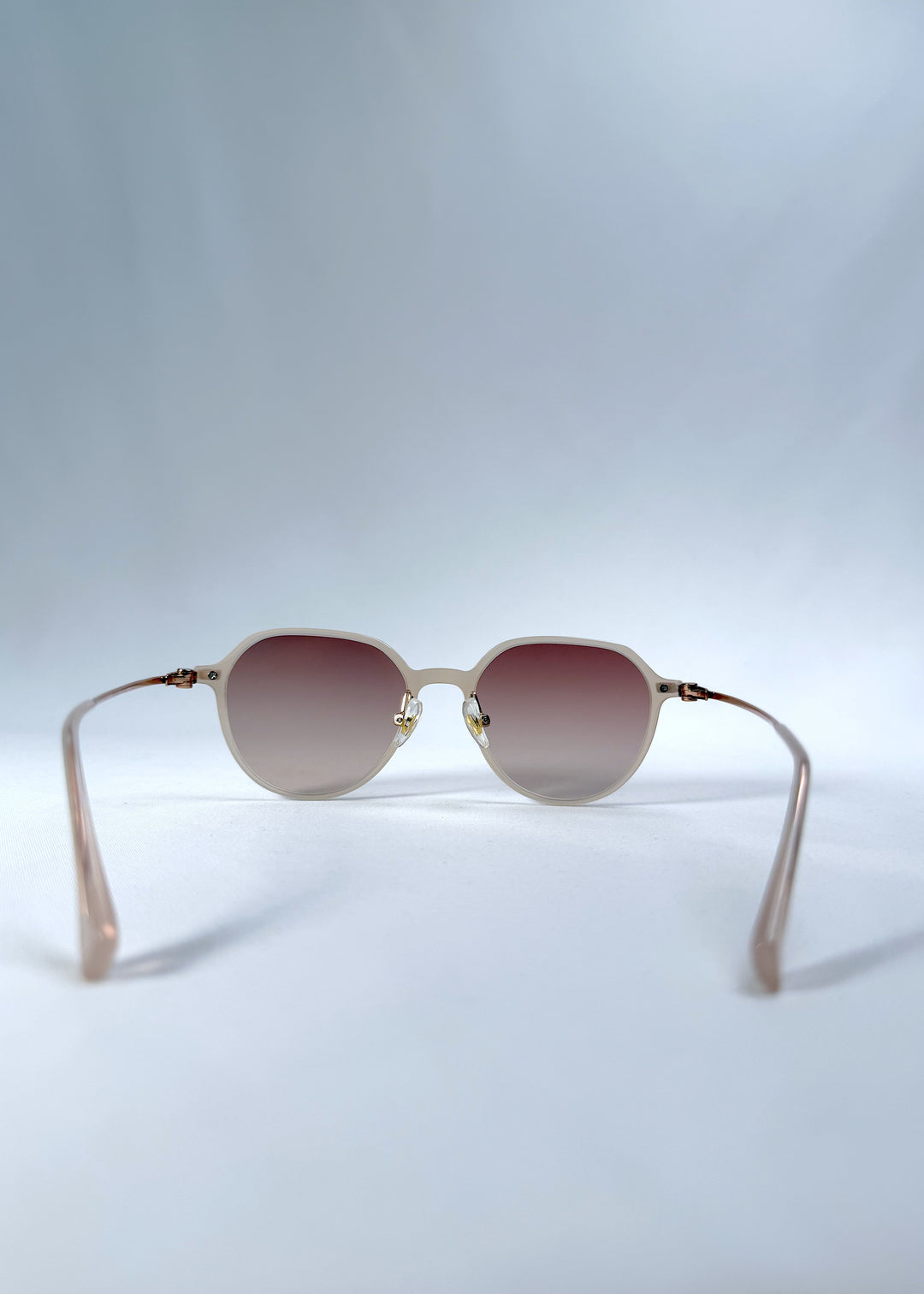 Back view of AZE Vireo Arc sunglasses in Roselight, featuring a translucent ivory frame and soft rose gradient lenses, showing the inner frame and open temples.