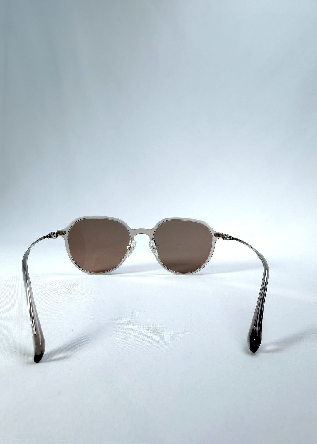 Back view of AZE Vireo Arc sunglasses in Taupe Rosé, featuring a translucent taupe frame and rose-brown gradient lenses, showing the inner frame and open temples.