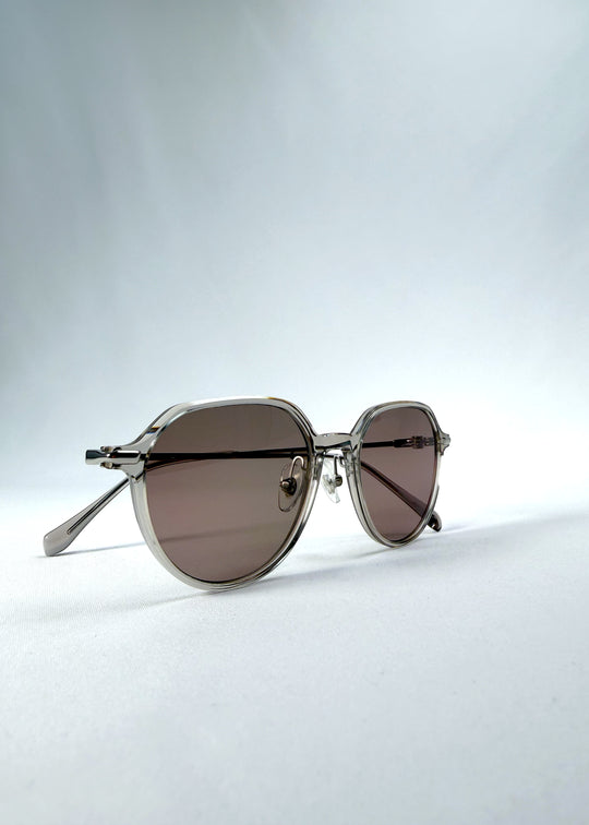 Folded view of AZE Vireo Arc sunglasses in Taupe Rosé, featuring a translucent taupe frame and rose-brown gradient lenses, showing the folded temples and frame profile.