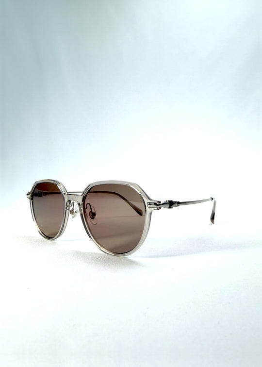 Three-quarter front view of AZE Vireo Arc sunglasses in Taupe Rosé, featuring a translucent taupe frame and rose-brown gradient lenses, showing the frame shape and temple profile.