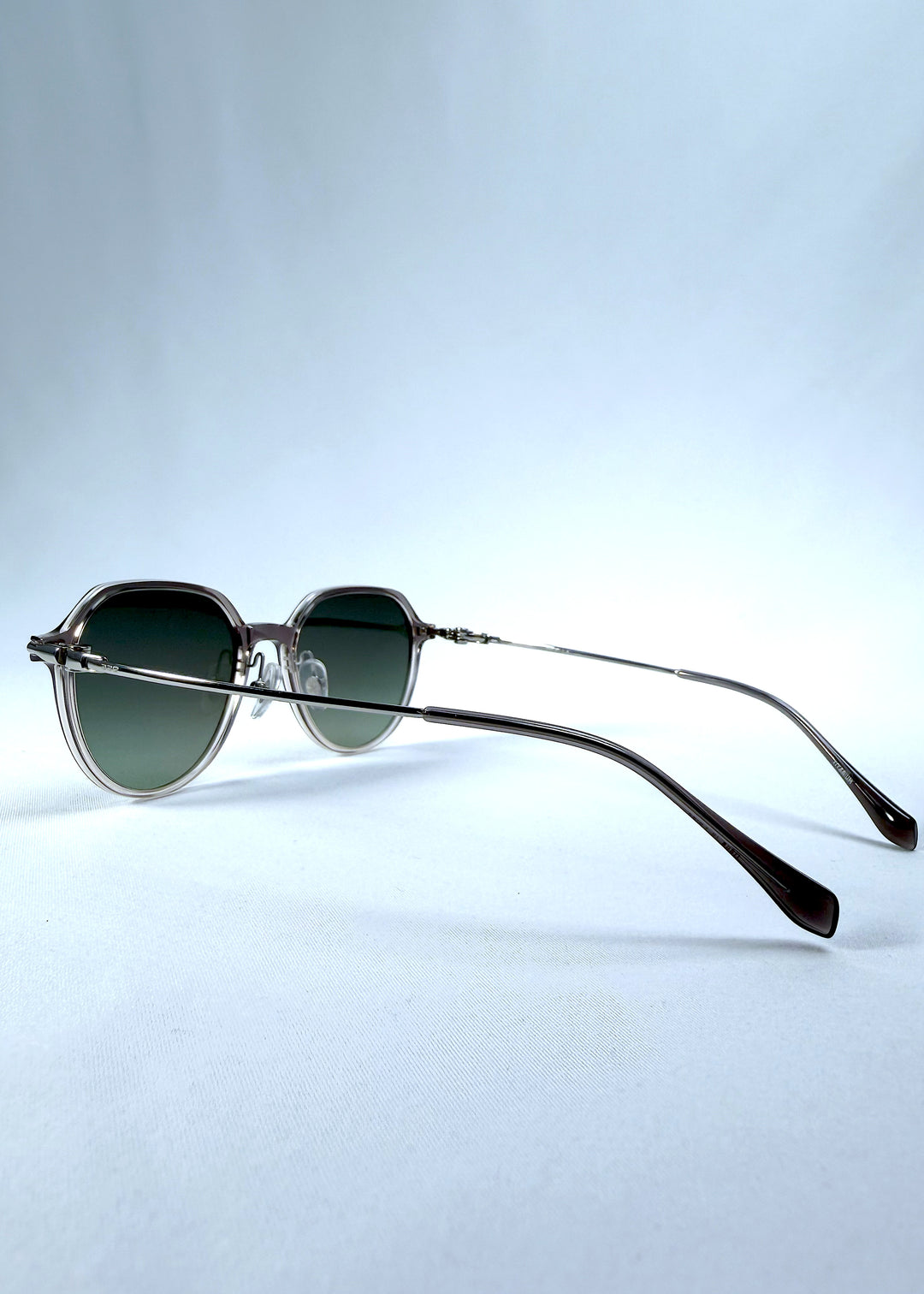 Back-angle view of AZE Vireo Arc sunglasses in Verdant Halo, featuring a translucent smoky mauve frame and green gradient lenses, showing the rear frame structure and temple alignment.