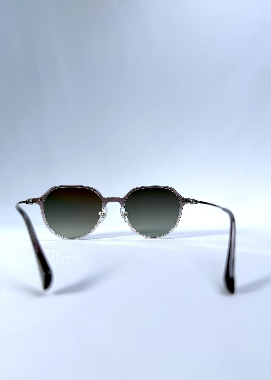 Back view of AZE Vireo Arc sunglasses in Verdant Halo, featuring a translucent smoky mauve frame and green gradient lenses, showing the inner frame and open temples.