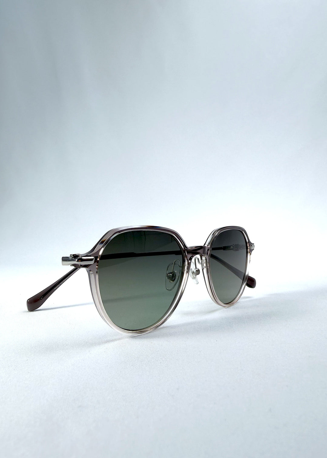Folded view of AZE Vireo Arc sunglasses in Verdant Halo, featuring a translucent smoky mauve frame and green gradient lenses, showing the folded temples and frame profile. 