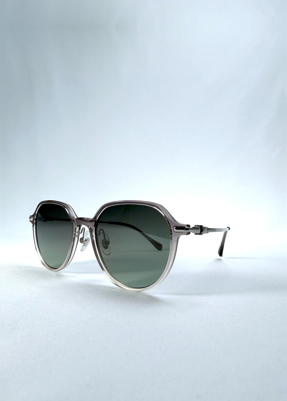 Three-quarter front view of AZE Vireo Arc sunglasses in Verdant Halo, featuring a translucent smoky mauve frame and green gradient lenses, showing the frame shape and temple profile.