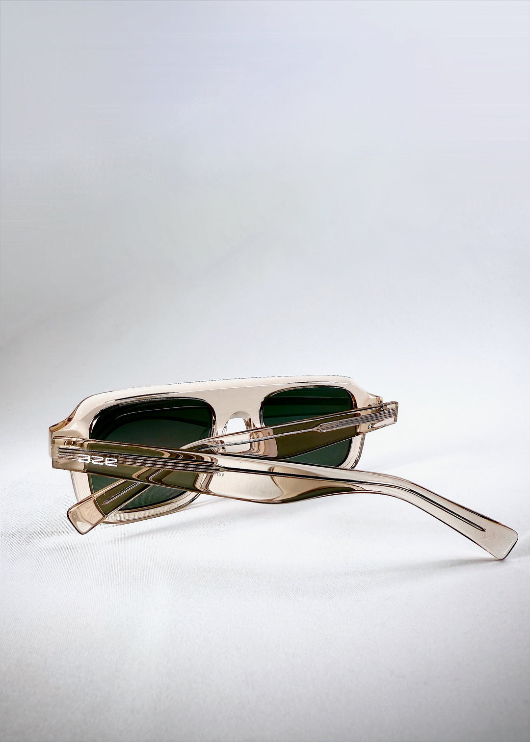Dynamic view of Vortex Edge - Champagne Glow sunglasses reflecting light on the transparent beige acetate. 