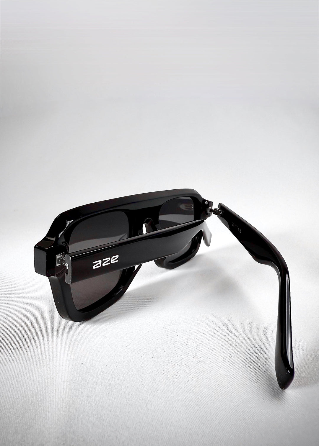 Close-up of folded Vortex Edge sunglasses in Obsidian Black, showcasing the glossy finish and hinge detailing. 