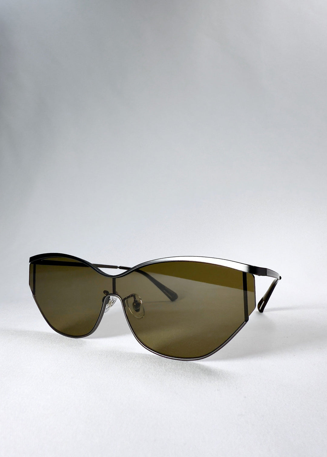 Three-quarter front view of Zenith sunglasses in Olive Smoke, highlighting the curved frame and olive lens tint. 