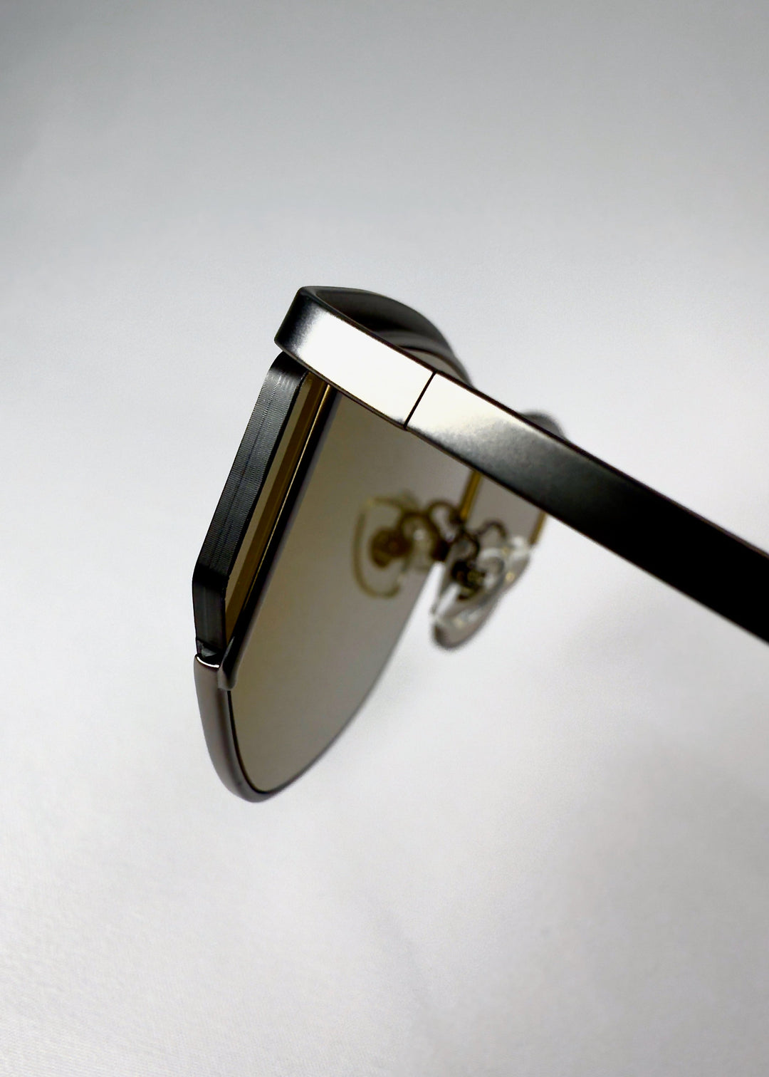 Close-up of the hinge on Zenith sunglasses in Olive Smoke, showing the metal frame and lens connection. 