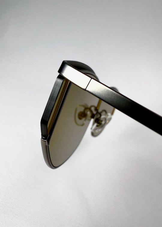 Close-up of the hinge on Zenith sunglasses in Olive Smoke, showing the metal frame and lens connection. 
